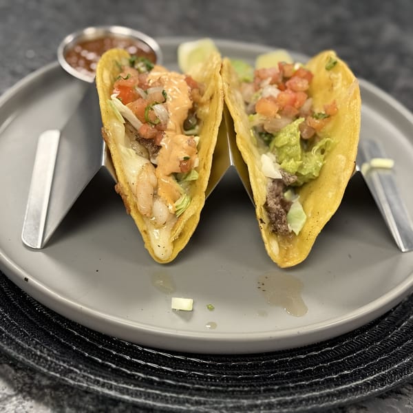 Two Itacate Mexican Food tacos, one with shrimp and sauce, the other with meat and guacamole.