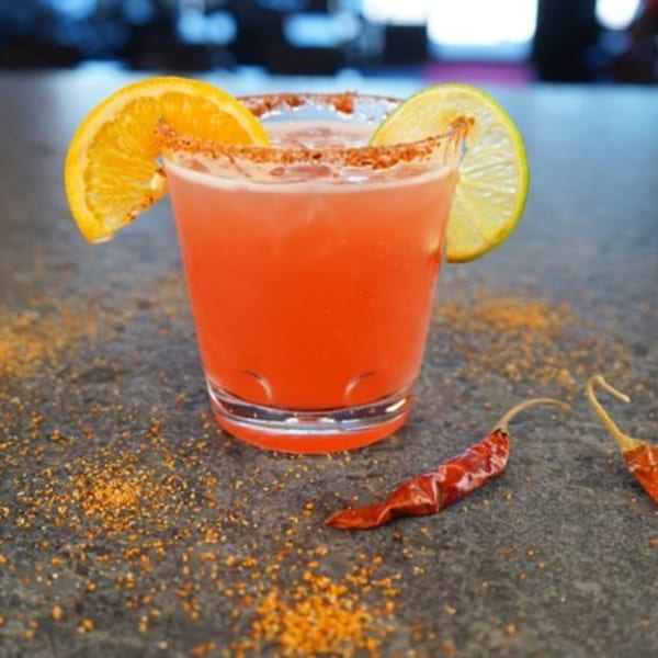 Itacate Mexican Food's red cocktail with orange and lime slices, chili powder, and dried chilies.